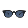 Front view of black square sunglasses with blue lenses showing thick frame, notched cutout bridge, and double silver rivets on temples